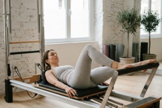 Femme pratiquant le Pilates Reformer dans le studio Poses à Paris 8 sur un appareil en bois et métal au design épuré